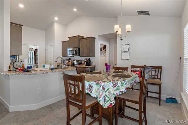 dining area with light tile patterned floors, baseboards, visible vents, an inviting chandelier, and high vaulted ceiling