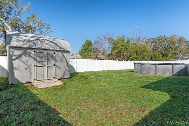 view of yard with a fenced backyard, a storage unit, an outdoor pool, and an outdoor structure