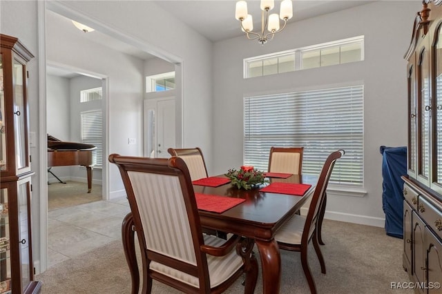 dining room with a chandelier, light colored carpet, and baseboards