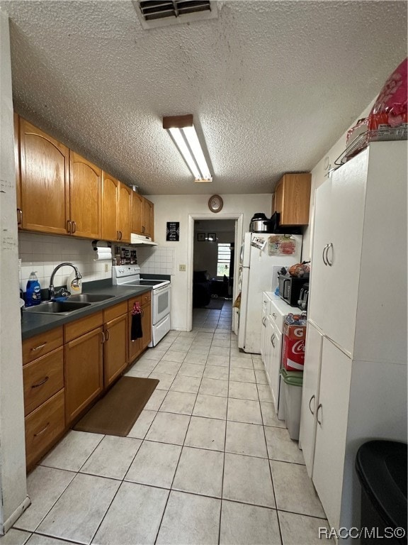 kitchen featuring white appliances, sink, light tile patterned floors, and tasteful backsplash