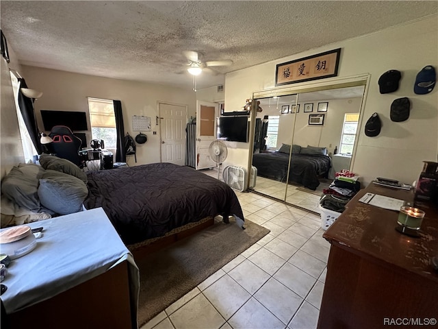 bedroom featuring multiple windows, light tile patterned floors, a textured ceiling, and ceiling fan