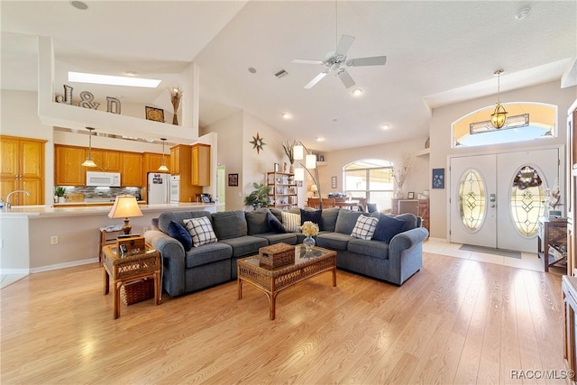 living room with ceiling fan, french doors, high vaulted ceiling, and light wood-type flooring