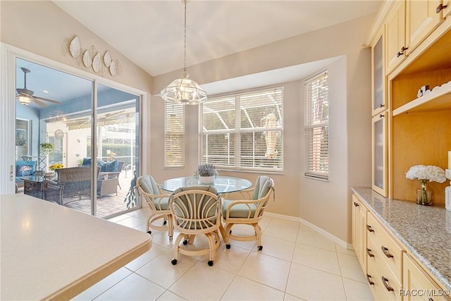 tiled dining room with ceiling fan with notable chandelier, a healthy amount of sunlight, and lofted ceiling