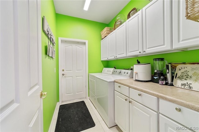 laundry area featuring washer and clothes dryer, cabinets, and light tile patterned floors