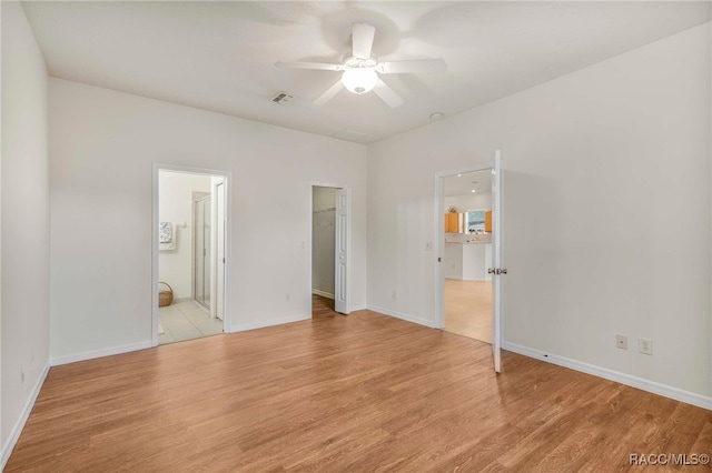 2459 N Brentwood Cir, Lecanto, FL 34461 - unfurnished bedroom with light wood finished floors, a walk in closet, connected bathroom, and ceiling fan