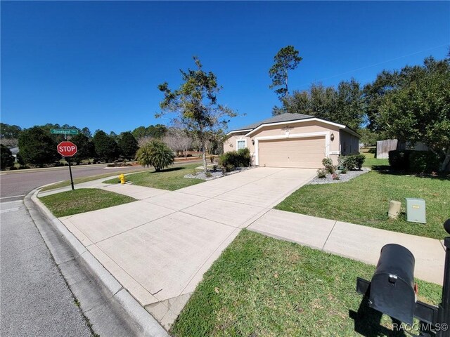 ranch-style home featuring concrete driveway, a front lawn, an attached garage, and stucco siding