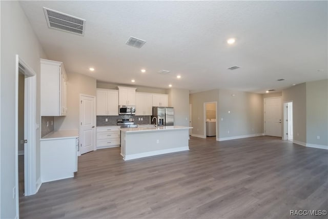 kitchen featuring appliances with stainless steel finishes, a kitchen island with sink, hardwood / wood-style floors, and white cabinets