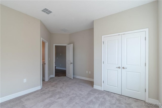 unfurnished bedroom featuring light carpet and a closet