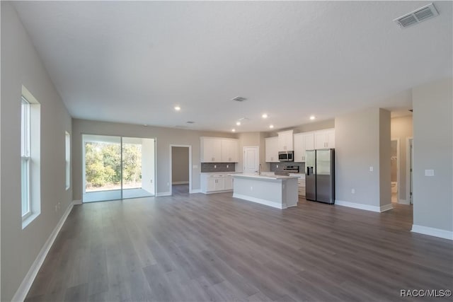 kitchen with appliances with stainless steel finishes, white cabinetry, an island with sink, sink, and light hardwood / wood-style flooring