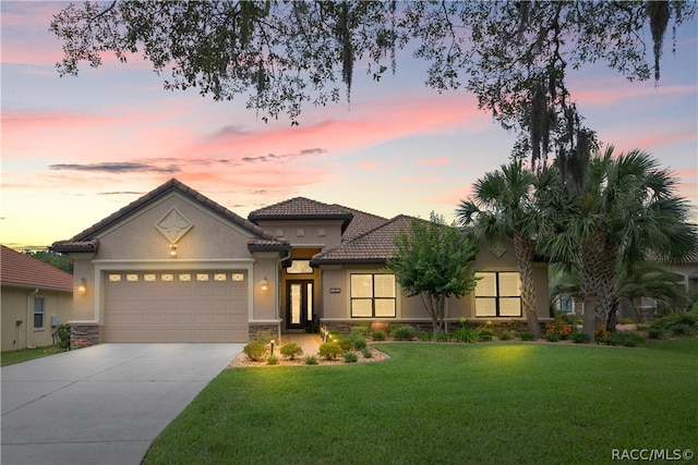 mediterranean / spanish-style house featuring a garage and a yard