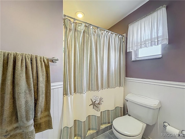 full bathroom featuring toilet, wainscoting, and a shower with shower curtain