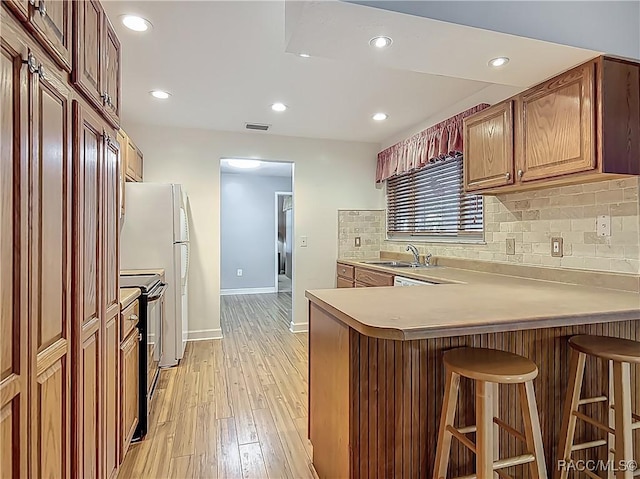 kitchen with decorative backsplash, a kitchen bar, baseboards, a peninsula, and electric stove