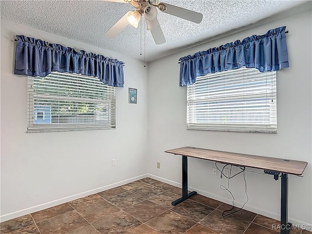 interior space with baseboards, ceiling fan, and a textured ceiling