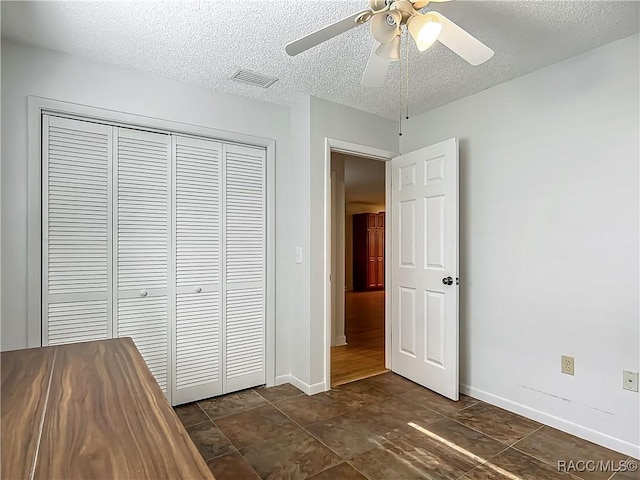unfurnished bedroom with visible vents, a textured ceiling, baseboards, and a closet
