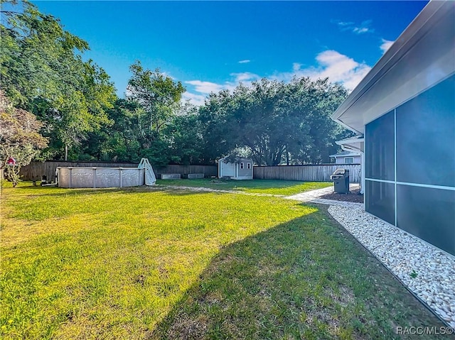 view of yard featuring a storage unit, a fenced backyard, an outdoor structure, and a pool