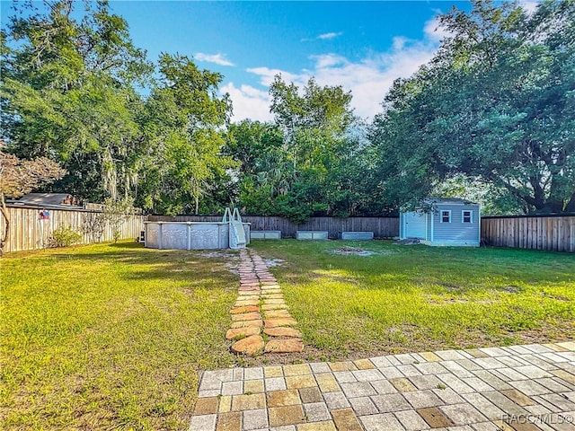 view of yard featuring a storage shed, a fenced in pool, an outdoor structure, and a fenced backyard