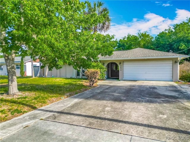 view of front of property featuring an attached garage, driveway, stucco siding, and a front yard