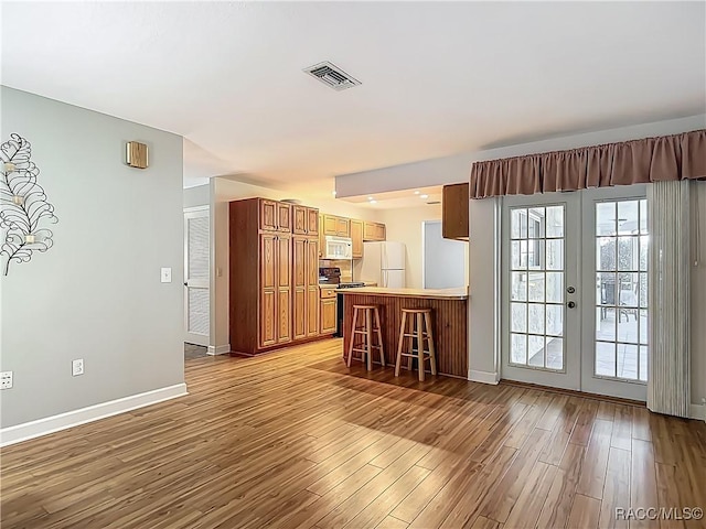 interior space featuring french doors, visible vents, wood finished floors, baseboards, and white appliances
