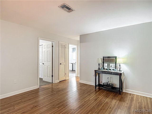 empty room featuring visible vents, baseboards, and wood finished floors