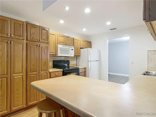 kitchen with visible vents, light countertops, decorative backsplash, and white appliances