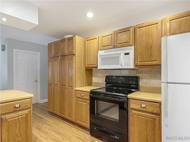 kitchen featuring light countertops, light wood-style flooring, backsplash, and white appliances