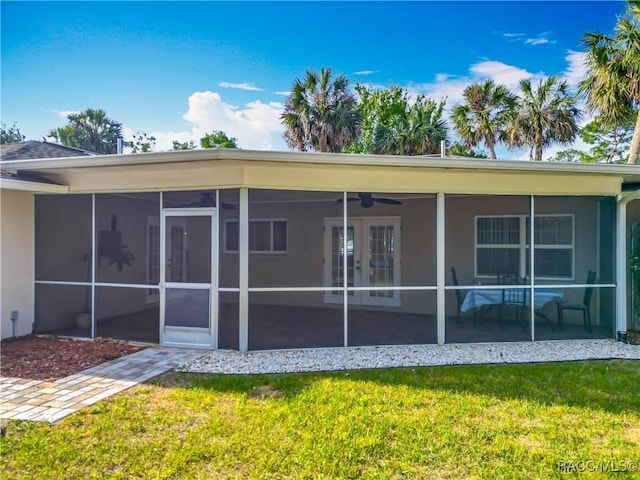 rear view of property featuring a yard, stucco siding, and a sunroom