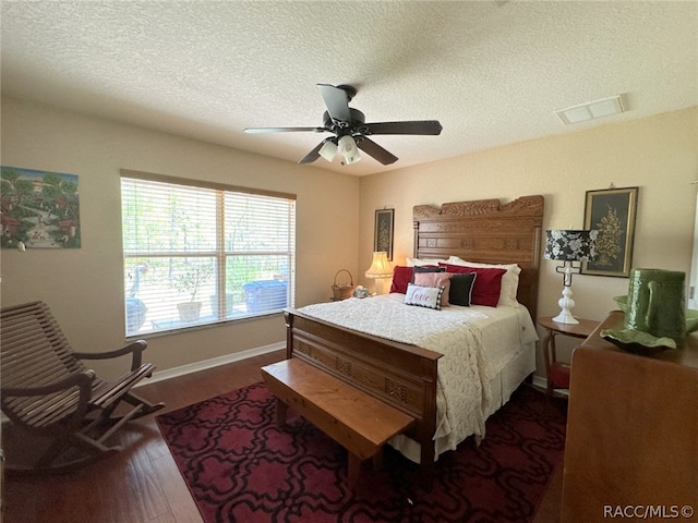 bedroom with a textured ceiling, ceiling fan, and dark hardwood / wood-style floors