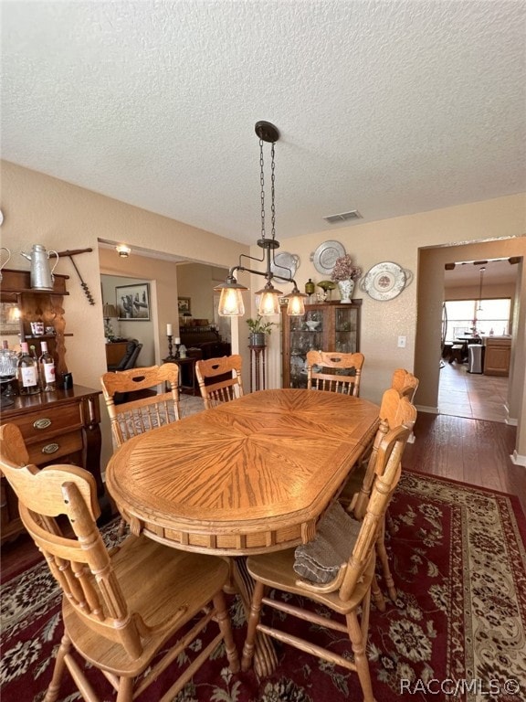 dining room with wood-type flooring and a textured ceiling