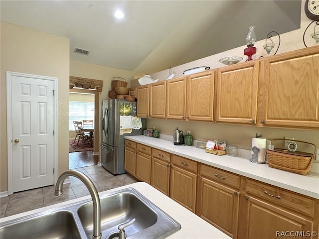 kitchen featuring stainless steel fridge, light hardwood / wood-style flooring, vaulted ceiling, and sink