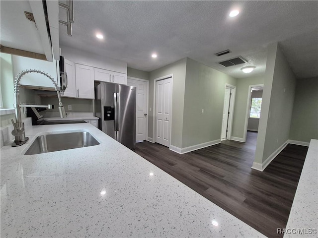 kitchen with white cabinets, light stone countertops, stainless steel fridge with ice dispenser, and a textured ceiling