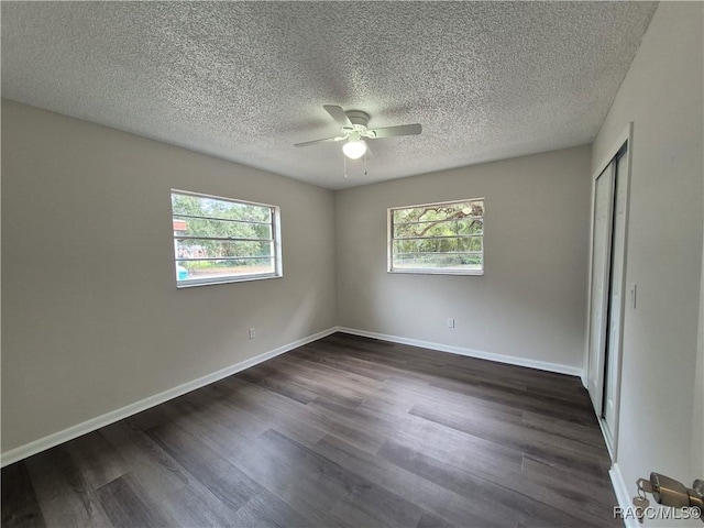 unfurnished room featuring ceiling fan, dark hardwood / wood-style floors, and a wealth of natural light