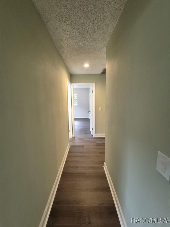 hall featuring a textured ceiling and dark hardwood / wood-style flooring