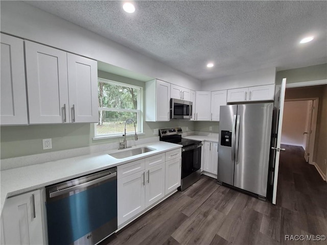 kitchen featuring a textured ceiling, dark wood-type flooring, white cabinetry, stainless steel appliances, and sink