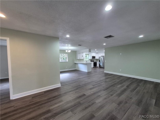 unfurnished living room featuring a textured ceiling, dark hardwood / wood-style flooring, and a notable chandelier