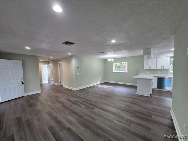 unfurnished living room featuring dark hardwood / wood-style floors, a chandelier, and a textured ceiling