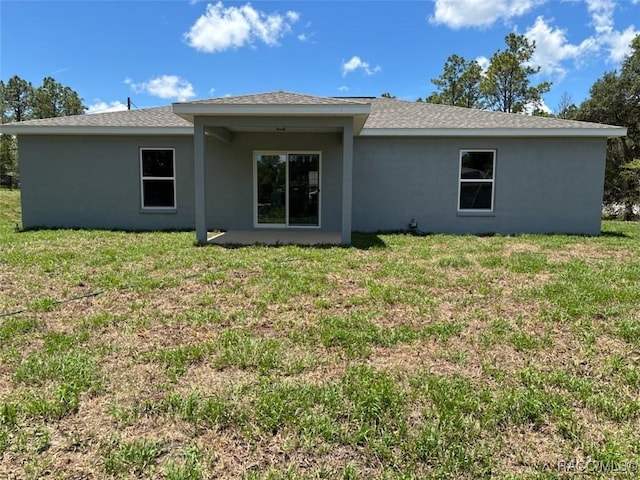 rear view of house featuring stucco siding and a yard