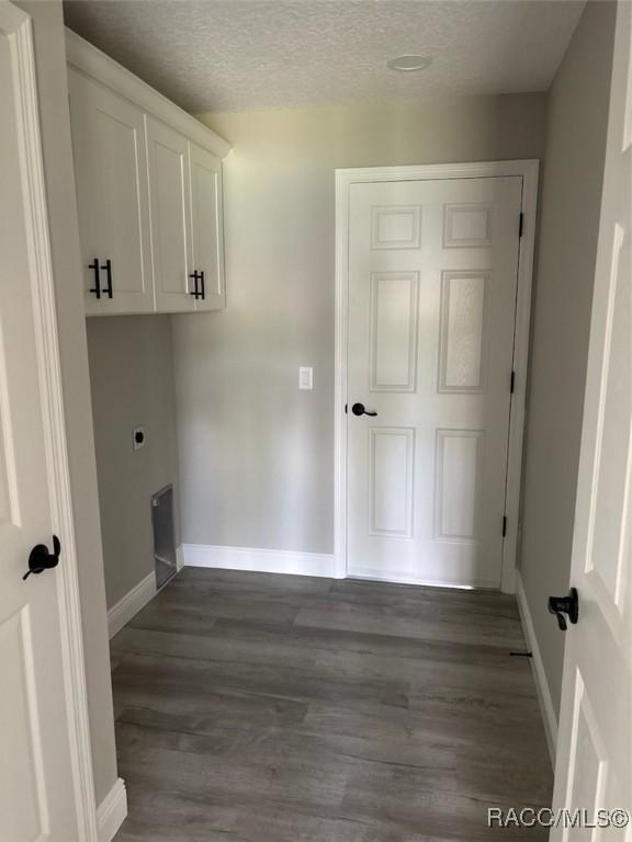 washroom with baseboards, cabinet space, dark wood finished floors, and a textured ceiling