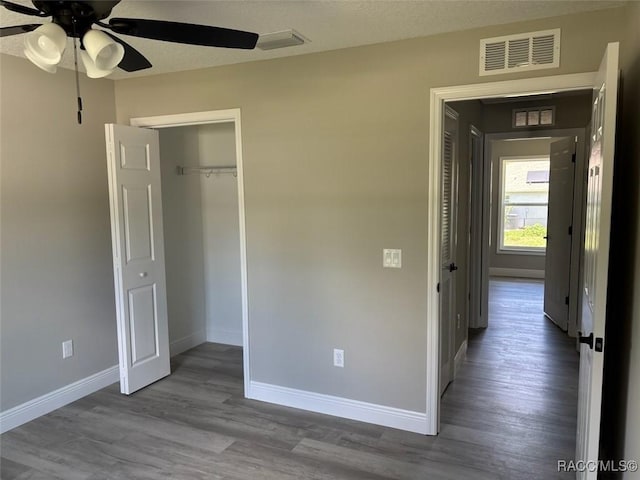 unfurnished bedroom with baseboards, wood finished floors, a closet, and ceiling fan