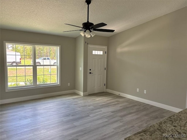 entrance foyer featuring a textured ceiling, wood finished floors, plenty of natural light, and baseboards