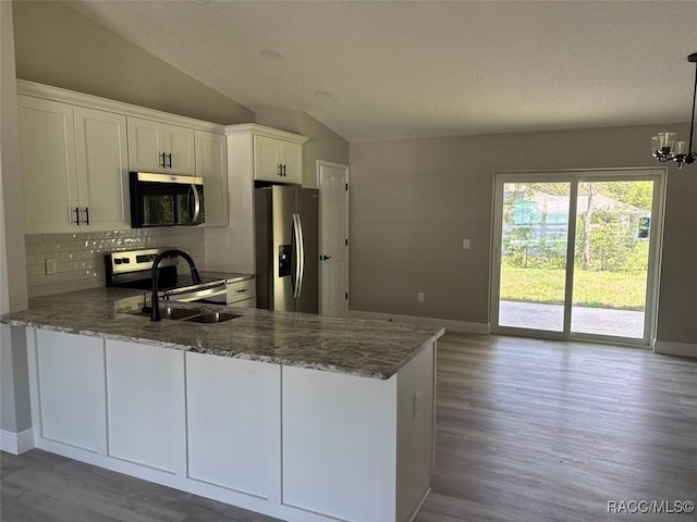 kitchen with stainless steel appliances, lofted ceiling, light stone counters, backsplash, and wood finished floors
