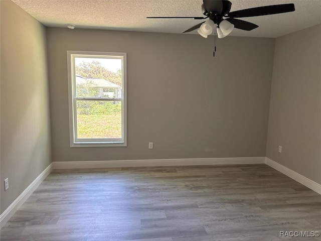 unfurnished room with a textured ceiling, wood finished floors, a ceiling fan, and baseboards