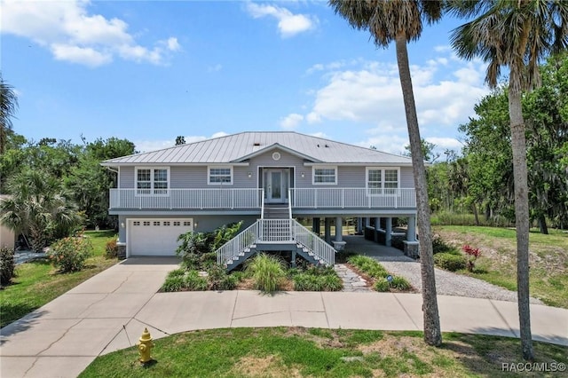 2168 N Watersedge Dr, Crystal River, FL 34429 - coastal home featuring concrete driveway, an attached garage, stairs, a metal roof, and covered porch