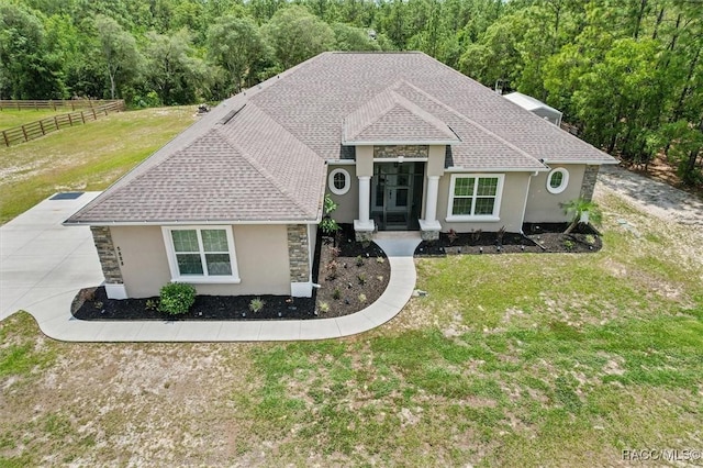 5888 W Corral Pl, Beverly Hills, FL 34465 - ranch-style home with stucco siding, stone siding, a shingled roof, and a wooded view
