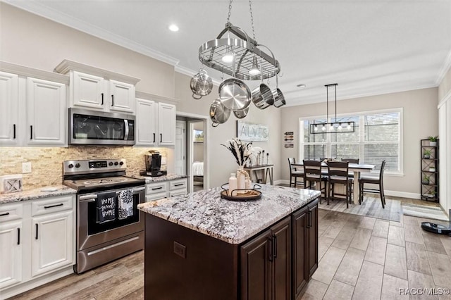 5888 W Corral Pl, Beverly Hills, FL 34465 - kitchen featuring stainless steel appliances, ornamental molding, backsplash, white cabinets, and a kitchen island