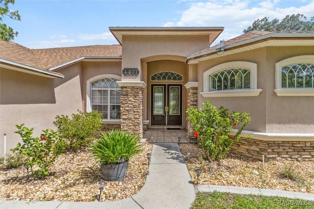 4491 W Stable Ct, Beverly Hills, FL 34465 - property entrance with stucco siding, stone siding, and a shingled roof
