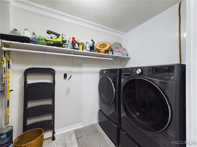 washroom with wood-type flooring, washing machine and dryer, a textured ceiling, and crown molding