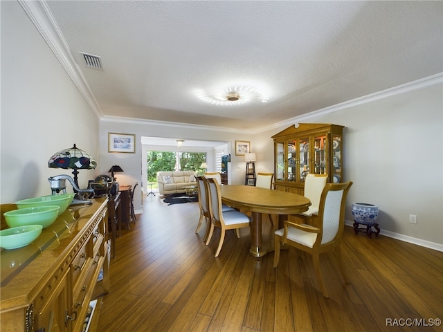 dining room featuring dark wood-type flooring, a textured ceiling, and ornamental molding