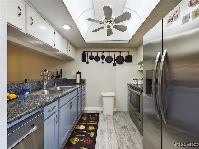 kitchen with white cabinetry, sink, dark stone countertops, appliances with stainless steel finishes, and light wood-type flooring