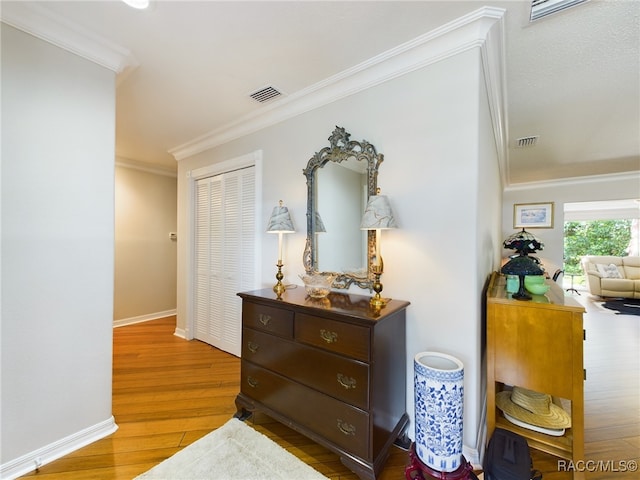 hall with ornamental molding and light hardwood / wood-style flooring