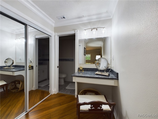 bathroom with vanity, a textured ceiling, crown molding, wood-type flooring, and toilet